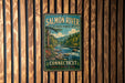 A vintage metal sign for the Salmon River State Forest in Connecticut, featuring a scenic image of a river surrounded by pine trees and mountains.