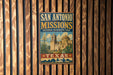A vintage-style sign for San Antonio Missions National Historical Park, featuring an illustration of the Mission San Antonio and the surrounding landscape.