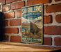 A vintage-style metal sign with a picture of two seals on a brick wall, advertising the San Guillermo Biosphere Reserve in Argentina.