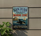 A vintage metal sign for San Juan Island National Historical Park, featuring an image of a whale and a sailboat, mounted on a wall.