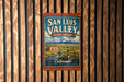 A vintage-style metal sign for San Luis Valley, Colorado, featuring a scenic landscape with mountains and a river.