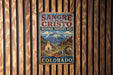 A vintage-style metal sign for the National Heritage Area in Colorado, featuring a mountain landscape and a church.