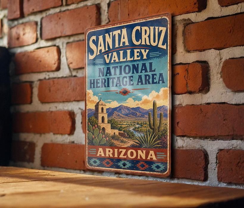 A vintage-style metal sign for Santa Cruz Valley National Heritage Area in Arizona, featuring a desert landscape with mountains, cacti, and a church bell tower.