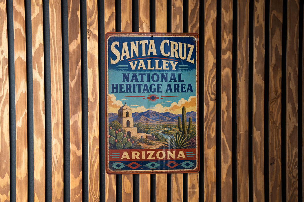 A vintage-style metal sign for Santa Cruz Valley National Heritage Area in Arizona, featuring a desert landscape with mountains, cacti, and a bell tower.