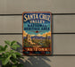 A vintage-style sign for Santa Cruz Valley National Heritage Area in Arizona, featuring a desert landscape with mountains, cacti, and a bell tower.