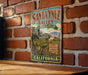 A vintage-style metal sign for Santa Ynez Valley, California, featuring a scenic illustration of vineyards and mountains.