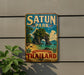A vintage-style sign for Satun Park in Thailand, featuring a tropical beach scene with palm trees and a rock formation.