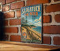 A vintage metal sign for Saugatuck Dunes State Park in Michigan, featuring a scenic beach landscape with a path leading to the beach.