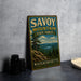 A vintage metal sign for Savoy Mountain State Forest in Massachusetts, featuring a scenic landscape with pine trees and a lake.