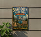 A vintage metal sign for the Sawtooth Lake Trail in Idaho, featuring a scenic mountain landscape and inviting visitors to explore the Sawtooth Mountains.