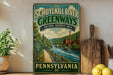 a vintage-style sign for the Schuykill River Greenways National Heritage Area in Pennsylvania, with a scenic illustration of a river, bridge, and forest.