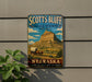 A vintage-style metal sign for the National Monument in Nebraska, featuring a wagon train and a mountain landscape.