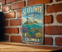 A vintage-style metal sign with a tropical island and sea turtle illustration, mounted on a brick wall.