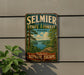 A vintage-style metal sign for Selmier State Forest in Indiana, featuring a scenic landscape with trees, a river, and a cloudy sky.