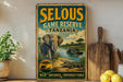A vintage-style metal sign advertising the Selous Game Reserve in Tanzania, featuring an illustration of an elephant and a crocodile in a natural setting.