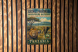 A vintage metal sign for the Serengeti-Ngorongoro Biosphere Reserve in Tanzania, featuring an illustration of a lion and elephants in a grassy savanna landscape.