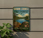 A vintage metal sign for Shawme-Crowell State Forest in Massachusetts, featuring a scenic landscape with a lake, pine trees, and a rock formation.