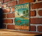 A vintage-style metal sign with the text "SIAN KÁAN MEXICO" and an illustration of a tropical island, palm trees, and a turtle swimming in the ocean.
