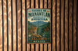 A vintage-style metal sign with a leopard and tropical plants, mounted on a wooden wall.