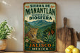 A vintage-style metal sign with a leopard and tropical landscape, advertising the Sierra de Manantlan reserve in Jalisco, Mexico.