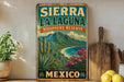 A vintage-style sign for Sierra La Laguna Biosphere Reserve in Mexico, featuring a scenic landscape with mountains, palm trees, and a beach.