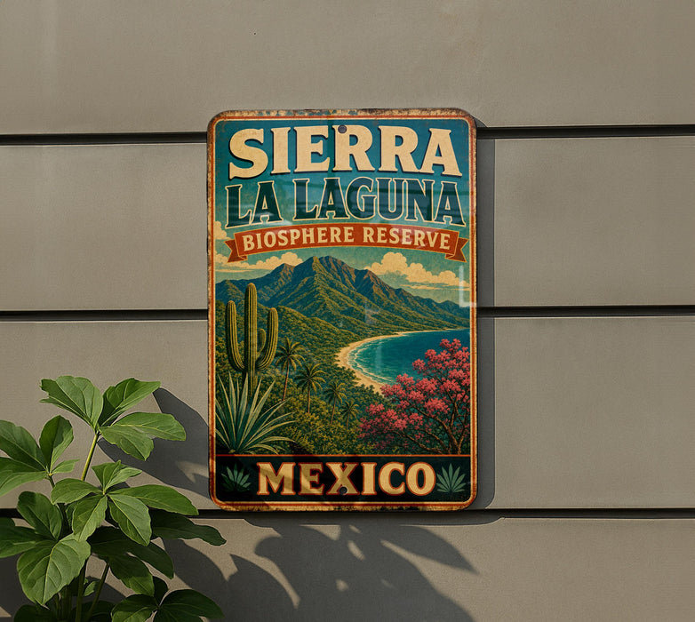 A vintage-style metal sign with the text "SIERRA LA LAGAÑA BIOSPHERE RESERVE MEXICO" and a scenic illustration of a tropical landscape with mountains, palm trees, and a beach.