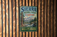 A vintage-style metal sign for Sierra National Forest in California, featuring a scenic landscape with mountains, pine trees, and a river.