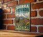 A vintage-style metal sign with the text "SIERRA NEVADA BIOSPHERE RESERVE SPAIN NATURE HERITAGE LIFE" is displayed on a brick wall.