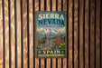 A vintage-style metal sign for Sierra Nevada Biosphere Reserve, featuring a mountain landscape with a goat and flowers, mounted on a wooden wall.