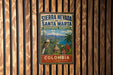 A vintage-style sign for Sierra Nevada de Santa Marta Biosphere Reserve in Colombia, featuring a tropical landscape with a bird and palm trees.