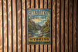 A vintage-style sign for Sinks Canyon State Park in Wyoming, featuring a scenic mountain landscape with a river flowing through it.