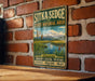 A vintage-style metal sign for Sitka Sedge, a state natural area in Oregon, is displayed on a brick wall.