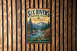 A vintage metal sign for the Six Rivers National Forest in California, featuring a scenic mountain landscape with a river flowing through it.