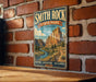 A vintage-style metal sign for Smith Rock State Park in Oregon, featuring a scenic illustration of the park's natural landscape.