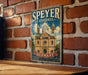 A vintage metal sign for Speyer Cathedral in Germany, featuring an illustration of the cathedral and the text "Speyer Cathedral" and "German".