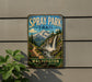 A vintage metal sign for the Spray Park Trail in Washington, featuring a scenic mountain landscape with a waterfall.