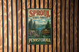 A vintage-style metal sign for the Sprout State Forest in Pennsylvania, featuring a scenic illustration of the forest and mountains.