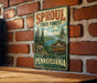 A vintage-style sign for the Sproul State Forest in Pennsylvania, featuring a scenic illustration of the forest and mountains.