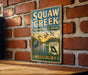 A vintage-style metal sign for Squaw Creek National Wildlife Refuge in Missouri, featuring a bird illustration and text about the refuge's mission.