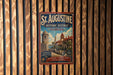 A vintage-style metal sign for St. Augustine, Florida, featuring a castle and palm trees, is displayed on a wooden wall.