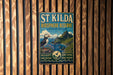 A vintage metal sign for St Kilda Bioscape Reserve, featuring a puffin bird and a scenic landscape, is displayed on a wooden wall.