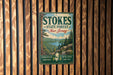 A vintage-style metal sign for Stokes State Forest in New Jersey, featuring a scenic landscape with pine trees, a lake, and mountains.