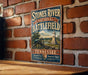 A vintage-style metal sign for the Stones River National Battlefield in Tennessee, featuring a cannon and a scenic landscape.