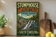 a vintage-style sign for Stumphouse Mountain Heritage Preserve, with a scenic image of a waterfall and a wooden cabin. The sign is displayed on a shelf next to a wooden cutting board and a potted plant.