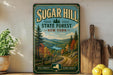A vintage-style sign for Sugar Hill State Forest in New York, featuring a scenic landscape with a winding road, pine trees, and a lake.