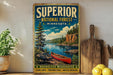 A vintage-style sign for Superior National Forest in Minnesota, featuring a canoe on a lake surrounded by pine trees and mountains.