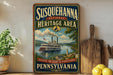 A vintage-style sign for Susquehanna National Heritage Area, featuring a steamboat on a river and a scenic landscape.