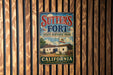 A vintage metal sign for Sutter's Fort State Historic Park in California, featuring an illustration of a historic building and the state flag.