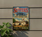 A vintage-style metal sign for Sutters Fort, a State Historic Park in California, featuring an illustration of a historic building and a California state flag.