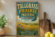 A vintage-style sign for Tallgrass Prairie Preserve in Oklahoma, featuring a scenic landscape with a bird in flight and flowers.